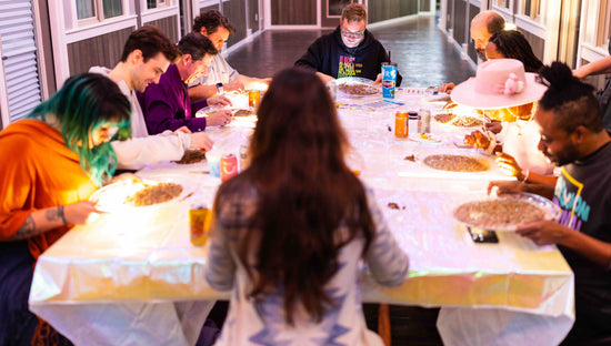 Ten sapphire mining guests sit around a table, leaning over light boxes and trays of gravel, searching for raw Montana sapphires at Glitter and Gold Studio. 